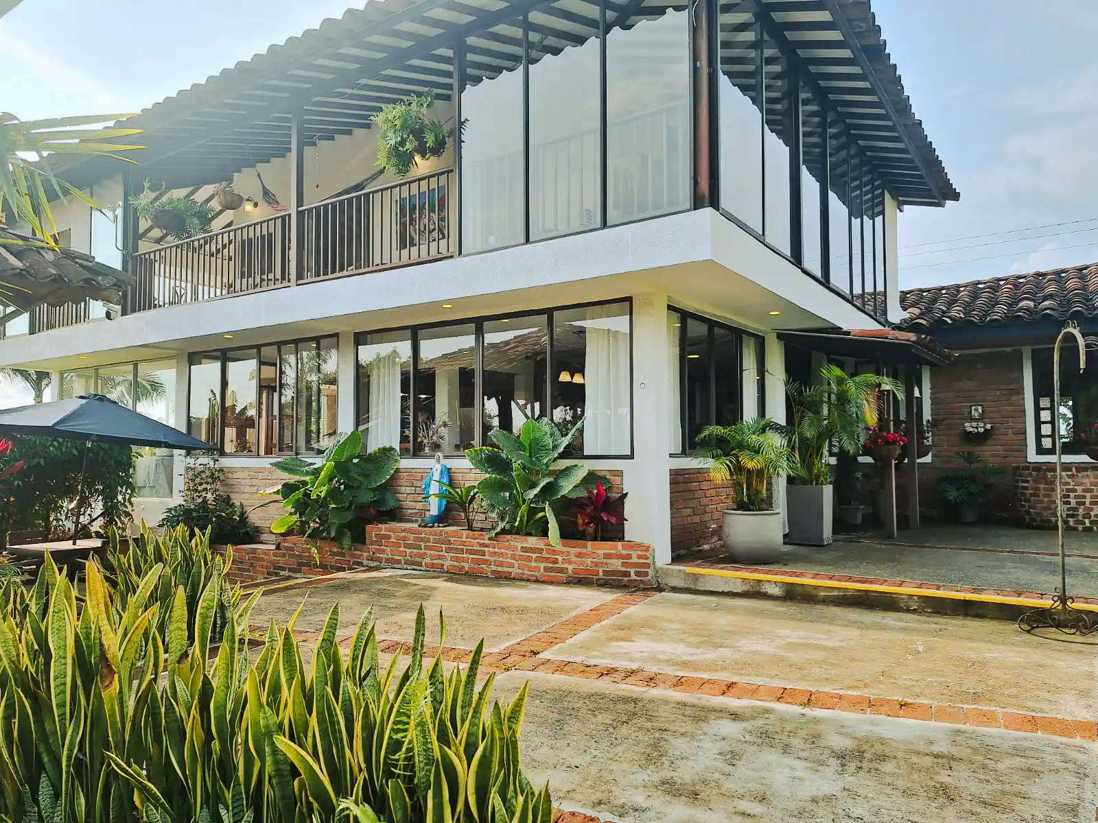 Casa finca hotel en Alcala Valle con fachada de cristal, balcones y jardines exuberantes.