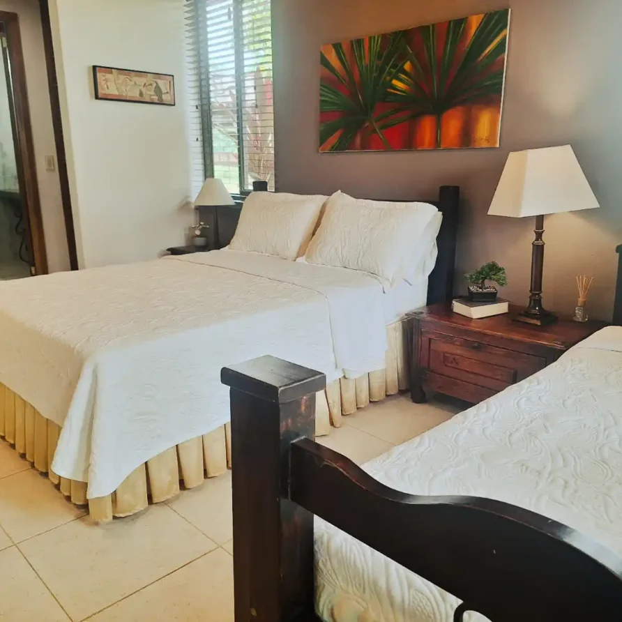 Habitación Junior Suite en Alcalá Valle con dos camas, decoración tropical, mesitas de noche y lámparas.