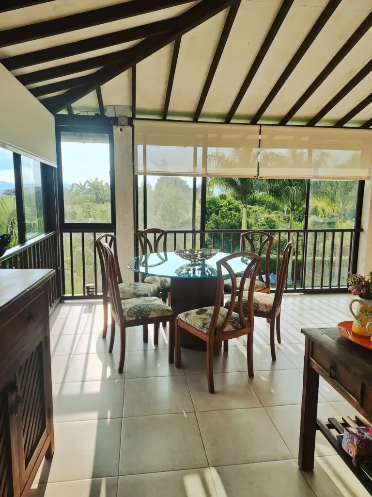 Área de comedor en segunda planta de casa finca con ventanales y vistas verdes, ideal para el alojamiento.
