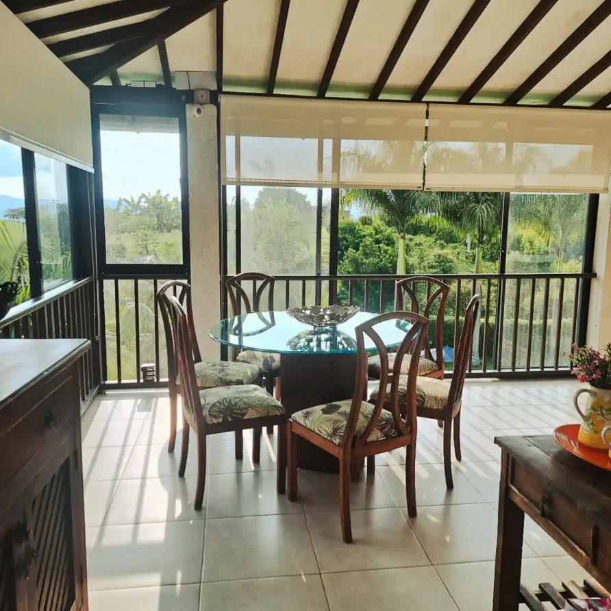 Área de comedor en segunda planta de casa finca con ventanales y vistas verdes, ideal para el alojamiento.