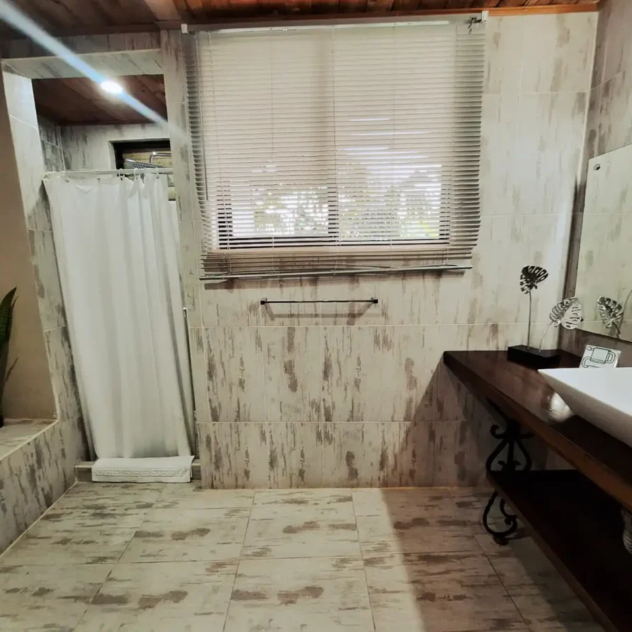 Cuarto de baño de lujo en alojamiento rural de Alcala Valle, con ducha, espejo y ventana con persianas.