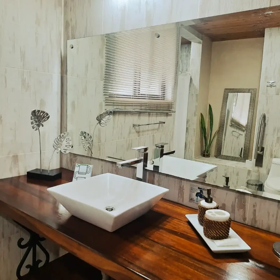 Diseño de baño de habitación junior suite con encimera rústica de madera y equipamiento contemporáneo en finca hotel.