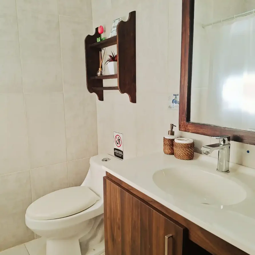 Baño moderno de habitación doble en hotel o finca en Alcalá, Valle del Cauca. Incluye lavabo, inodoro y espejo.