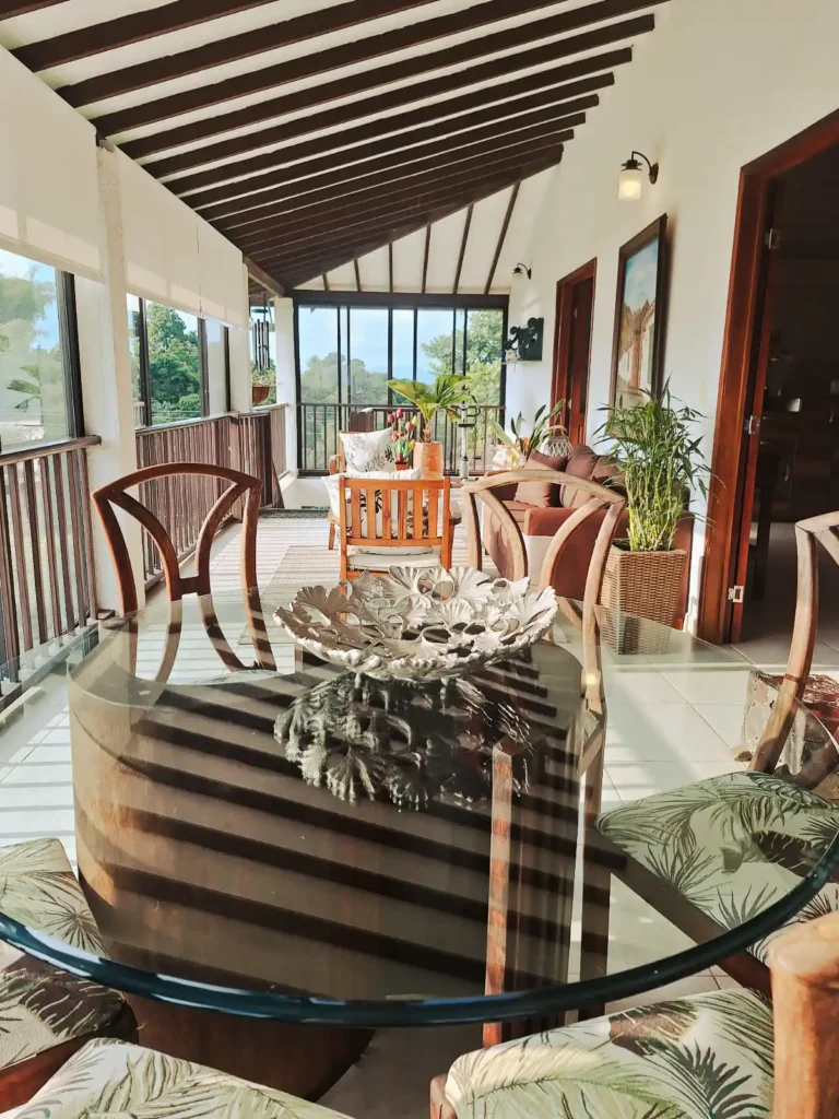 Espaciosa terraza de hotel o finca en Alcalá Valle con mesa de cristal, sillas de madera y vista a la naturaleza.