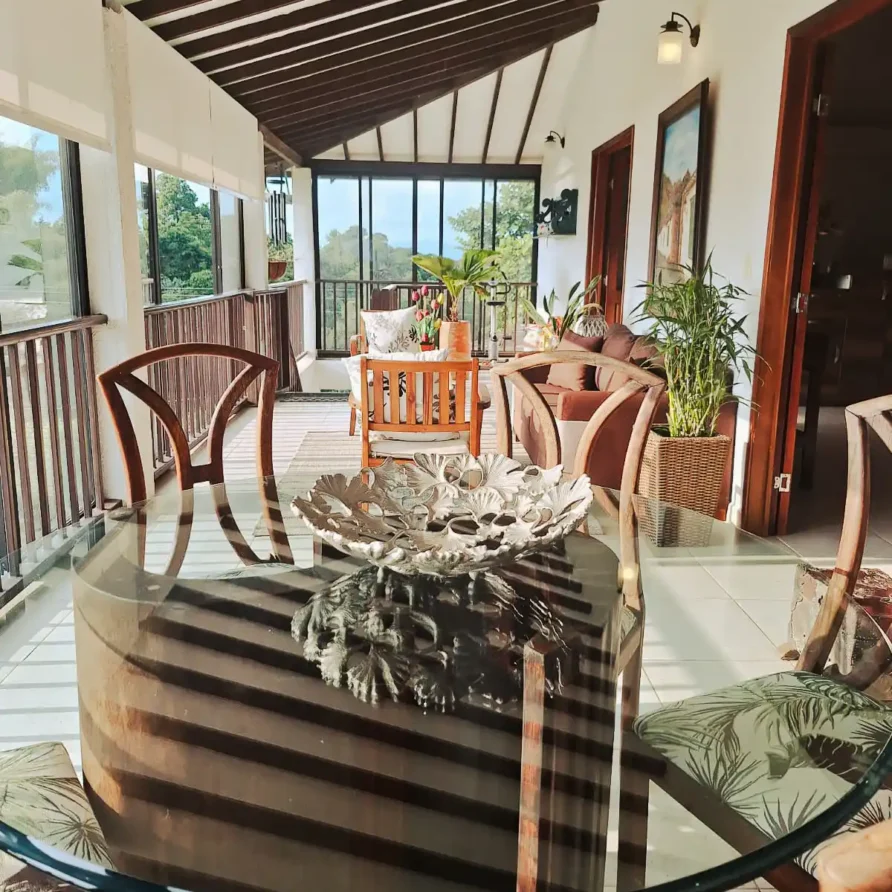 Espaciosa terraza de hotel o finca en Alcalá Valle con mesa de cristal, sillas de madera y vista a la naturaleza.