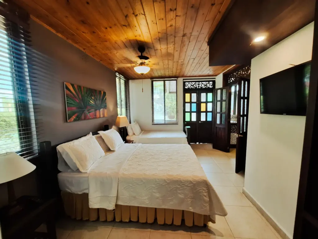 Amplia habitación en casa finca hotel Alcalá con cama queen, individual, TV y puertas de madera. Hospedaje familiar.