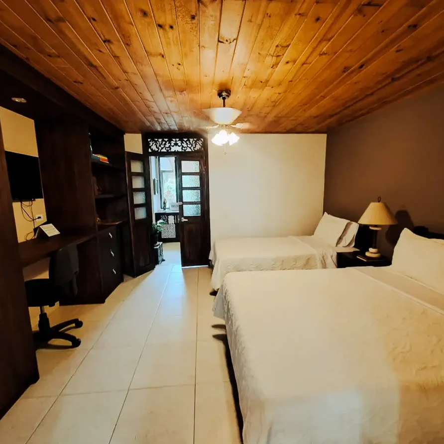 Suite cómoda con dos camas, mobiliario rústico de madera y ventilador, ideal para hospedaje en Alcala.