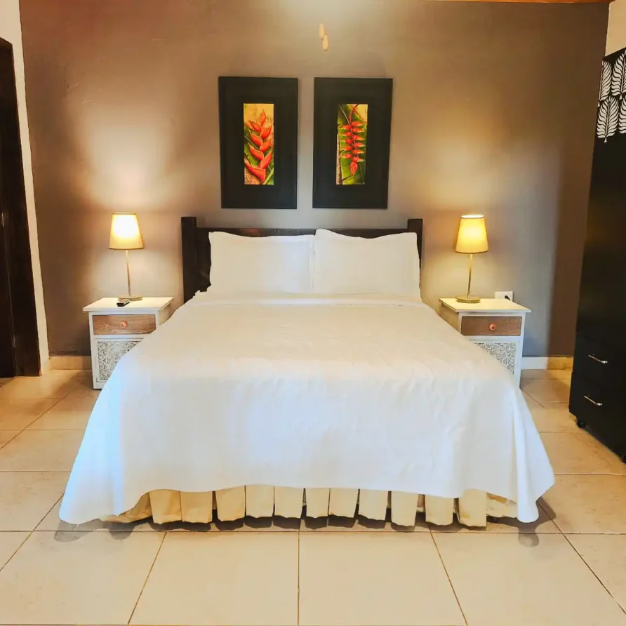Habitación suite familiar con cama king, decoración tropical y mesitas de noche en hotel de Alcalá, Valle del Cauca.