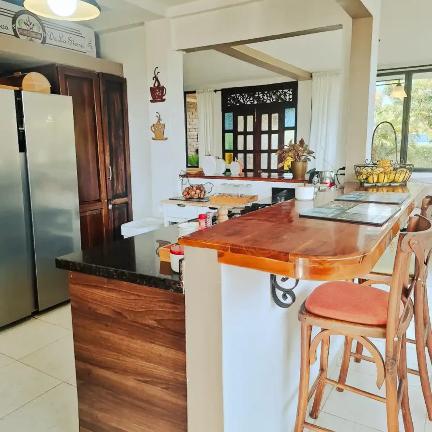 Cocina con barra de madera y sillas en una casa finca hotel, ideal para alojamiento en Alcalá, Valle del Cauca.