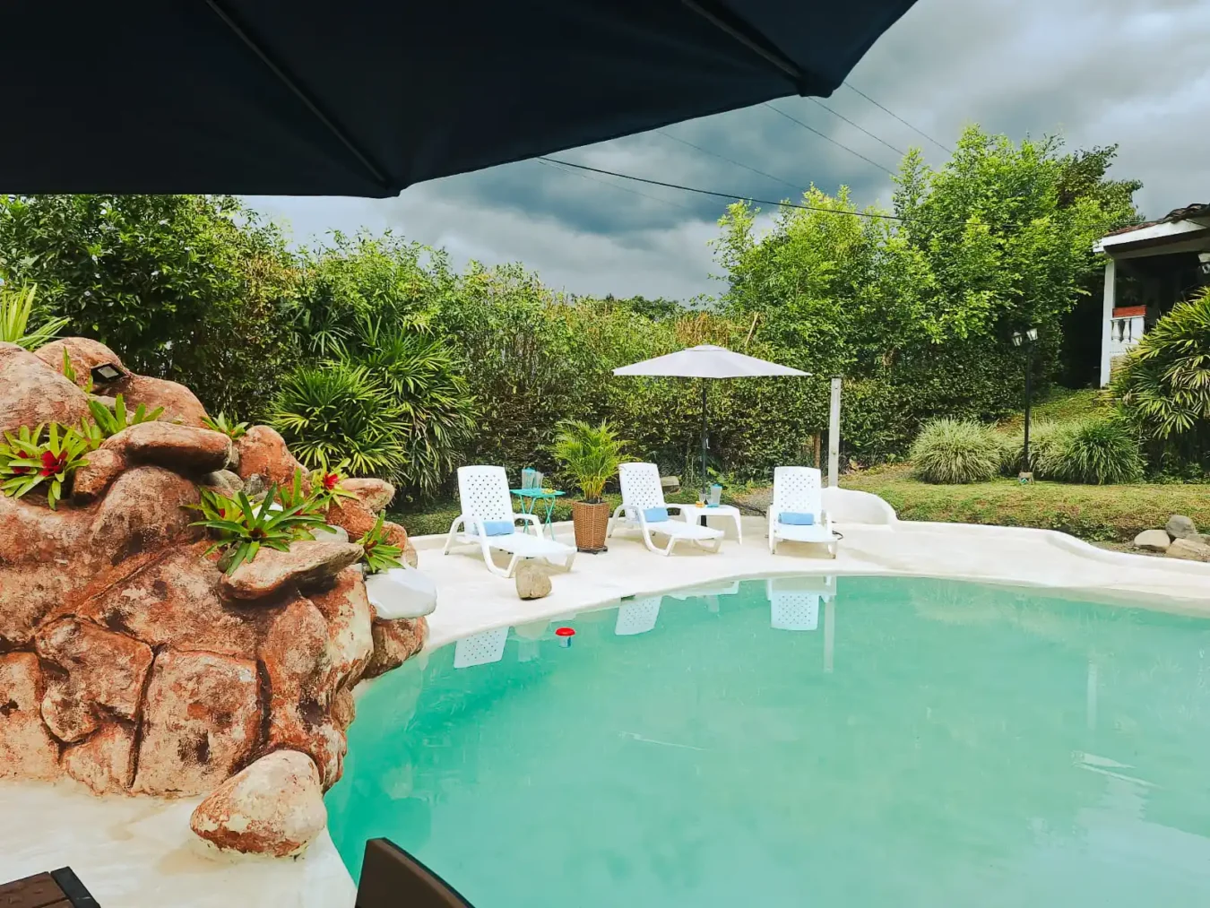 Área de piscina exterior en casa finca Alcalá Valle para alojamiento, con solárium y exuberante vegetación.