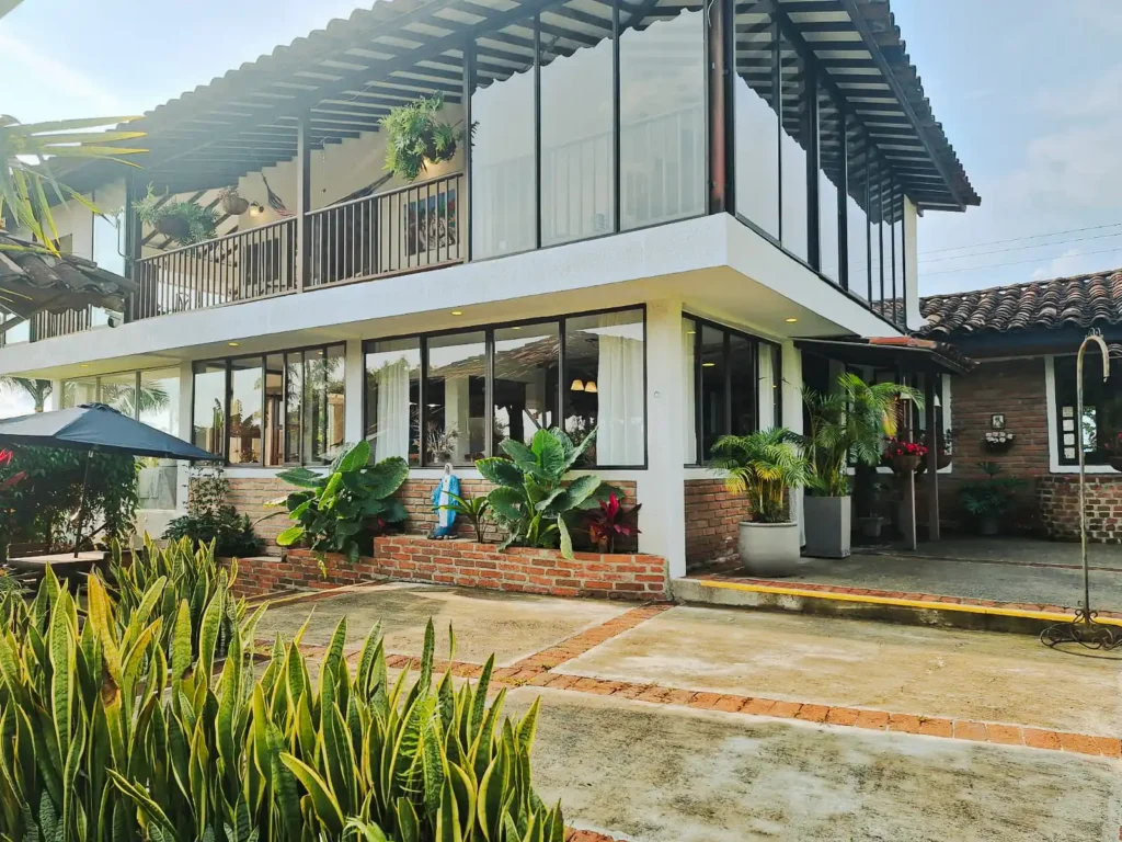 Casa finca hotel en Alcala Valle con fachada de cristal, balcones y jardines exuberantes.