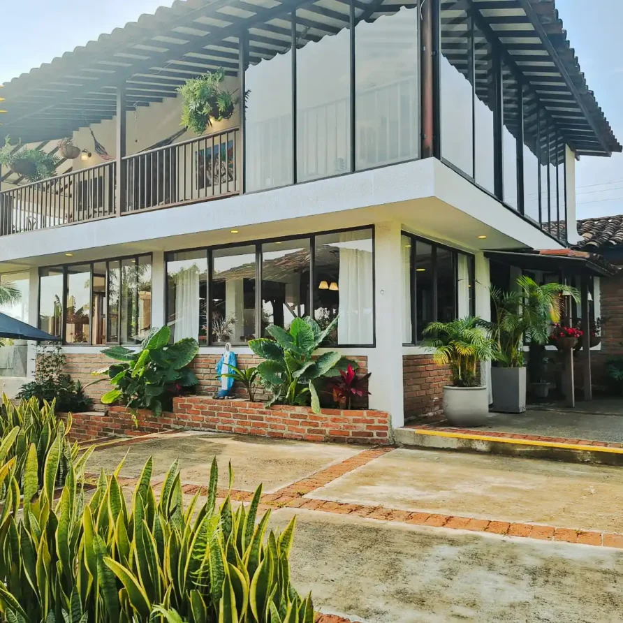 Casa finca hotel en Alcala Valle con fachada de cristal, balcones y jardines exuberantes.